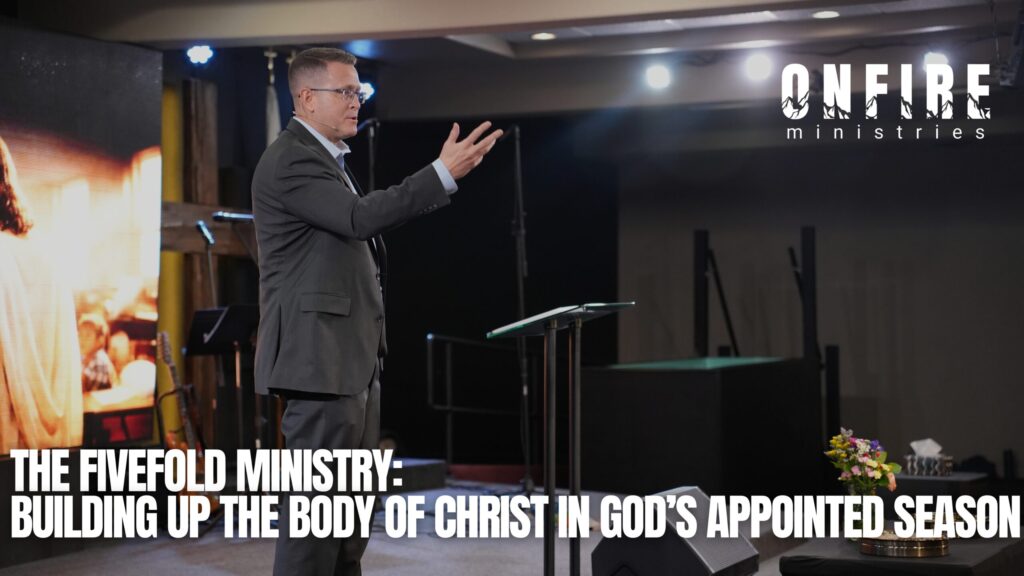 Graphic for OneFire Ministries showing a male preacher in a suit speaking on a church stage and gesturing with one hand beside a lectern. Stage lights, a large screen, instruments, and flowers are visible in the background. Large white text reads, ‘The Fivefold Ministry: Building Up the Body of Christ in God’s Appointed Season,’ with the OneFire Ministries logo in the upper right.